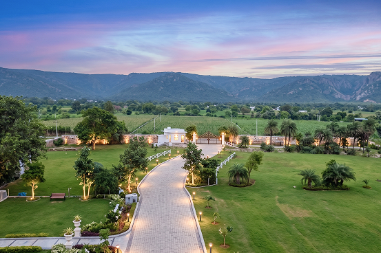 Palms & Pebbles — lit path through lawns toward the hills