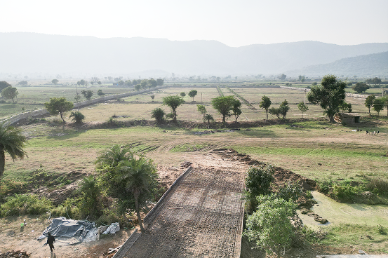 Palms & Pebbles — aerial view of road and plots at sunset